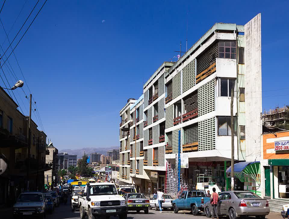 A four-storey apartment block with louvred balconies above a busy Addis Ababa street